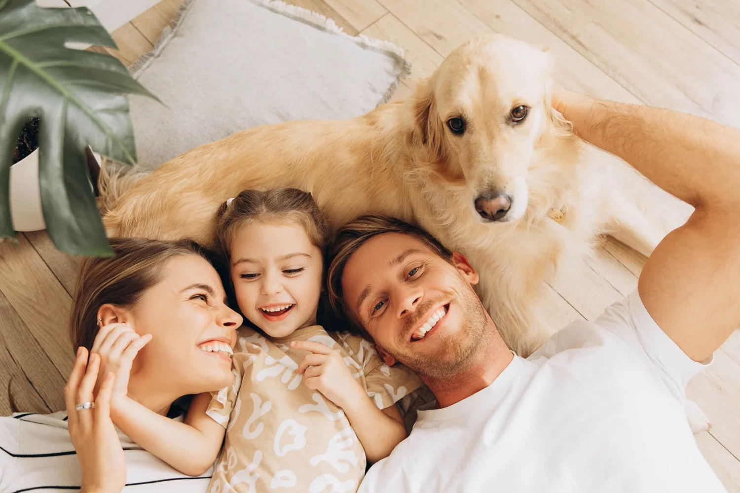 Family laying on the ground with a dog and child smiling